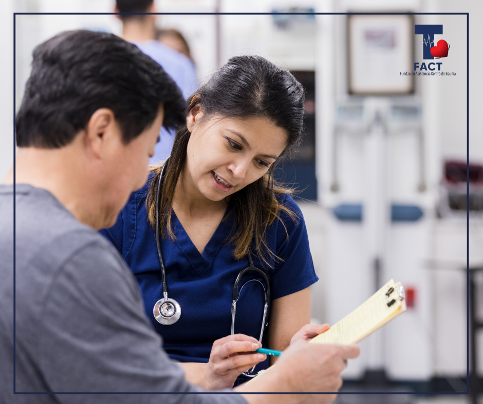 Profesional de la salud explica información clínica a un paciente mientras revisan un documento, como parte del proceso de consentimiento informado.