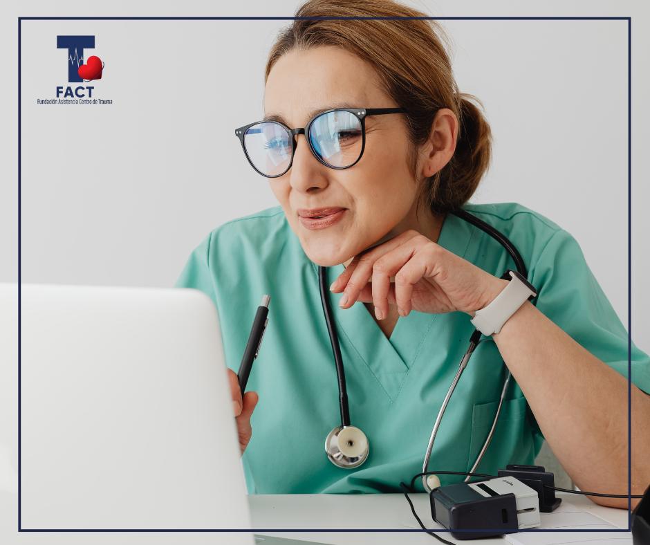 Residente de salud con uniforme verde revisa información en una computadora portátil, representando el estudio y la organización académica durante la residencia médica.