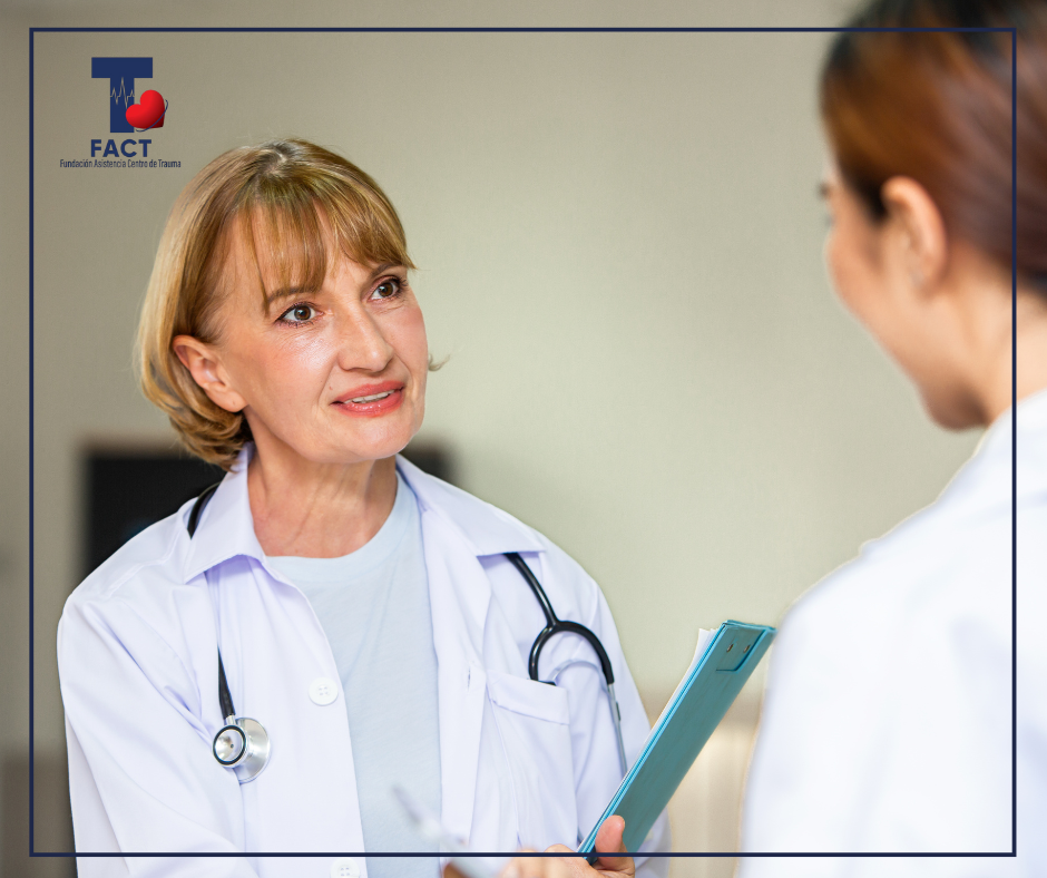 Médica conversa con otra profesional de la salud mientras revisa información clínica, destacando la comunicación directa entre especialistas en un entorno hospitalario.